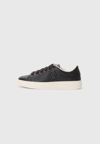 Sorte lær sneakers med rund tå, kontrasterende kremfarget såle, m�ørke snørebånd og preget logo detalj på siden. Jevn tekstur generelt.