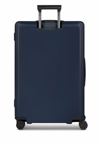 Maleta rígida azul marino con superficie texturizada, asa retráctil y cuatro ruedas negras para facilitar la movilidad. Diseño compacto y minimalista.