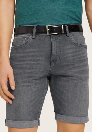 Shorts en denim gris avec revers, poches avant et une ceinture en cuir noir avec une boucle en argent. Longueur courte et design ajusté.