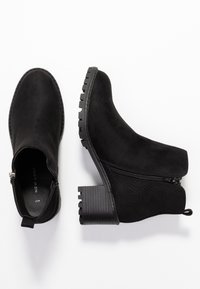 Stivaletti neri in suede con tacco spesso impilato. Presentano una cerniera laterale e un pannello testurizzato per un tocco di dettaglio in più.