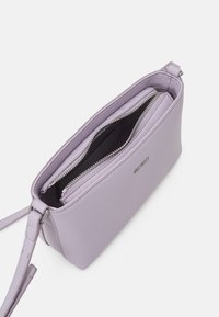 Lila läderväska med dragkedjestängning, med en slät yta och en smal design. Inuti finns en mjuk foder och en extra dragkedjeficka.