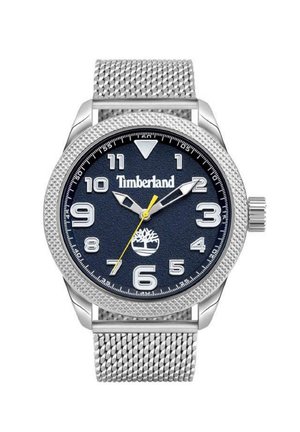 Montre à bracelet en maille argentée avec un cadran texturé bleu marine, des chiffres blancs et une aiguille des secondes jaune. Logo Timberland affiché sur le cadran.
