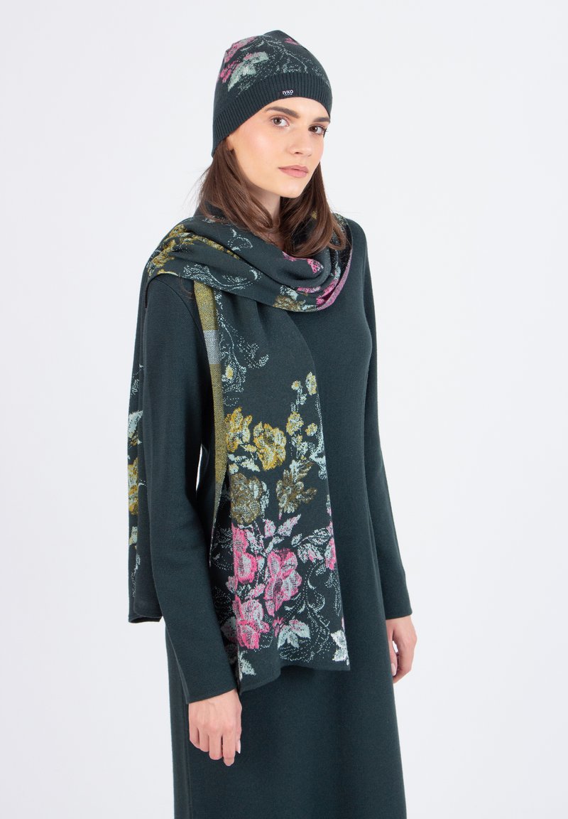 Abito lavorato a maglia verde scuro con una sciarpa a pattern floreale multicolore e berretto abbinato, caratterizzato da una texture morbida e una vestibilità comoda.