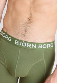 Green cotton boxer briefs with a wide white logo waistband, featuring a snug fit and flat seams for comfort.