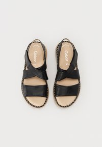 Sorte lær sandaler med kryssende stropper, en polstret beige såle og en flettet såledetalj. Utformet for komfort og pusteevne.