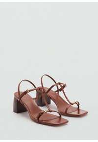 Bruna lädersandaler med fyrkantig tå, tunna remmar och klack i blockstil. Guldtonade detaljer och en mjuk yta.