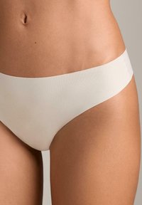 Nahtlose, dehnbare hellbeige Unterhosen mit breitem Bund, für Komfort entworfen. Glatte Textur, minimaler Bedeckungsstil.