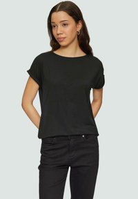 Zwarte T-shirt met korte mouwen, gemaakt van zachte stof, met een relaxed fit en een ronde halslijn, gecombineerd met donkere jeans.