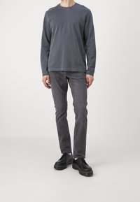 Grå långärmad tröja i mjukt tyg, kombinerad med grå jeans och svarta skor med tjocka sulor. Enkelt design, utan mönster eller tydliga detaljer.