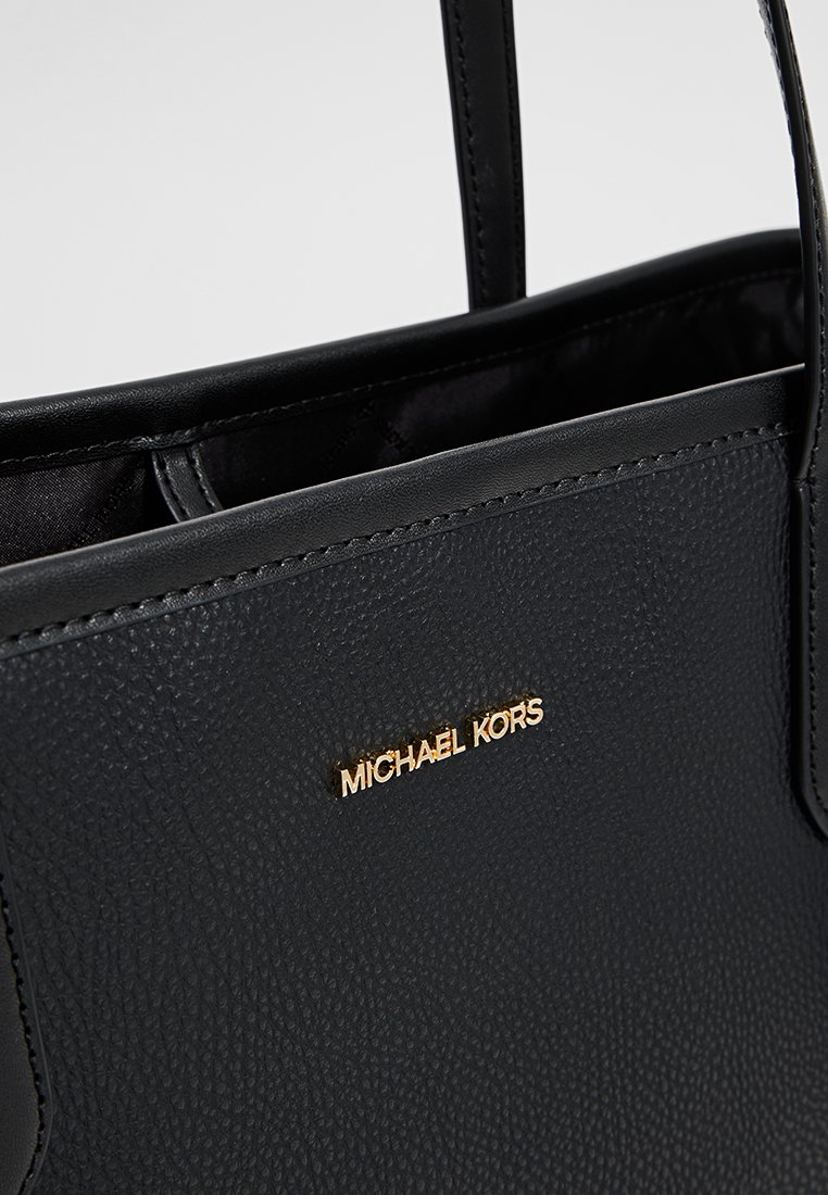 Zwarte handtas van textuurleer met twee handgrepen. Kenmerkt een gouden logo plaat "MICHAEL KORS" aan de voorkant. De binnenkant bevat een gevoerd compartiment.