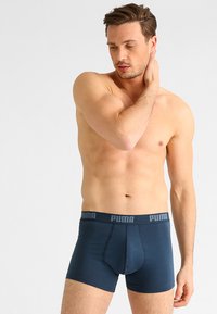 Boxer briefs azul marino hechos de una tela suave; cinturilla elástica con el logo 'PUMA' en gris; diseño ajustado con una parte frontal contorneada.