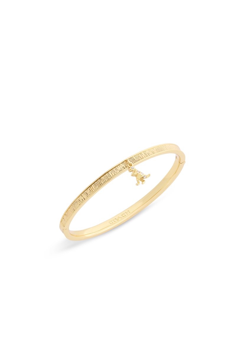 Pulsera de bangles de metal en tono dorado con una forma suave y redondeada, detalles grabados y un pequeño colgante en forma de perro.