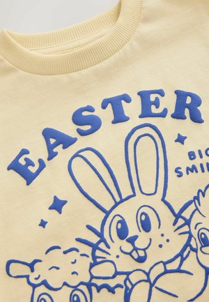 Yellow sweatshirt featuring blue printed graphics of a bunny and characters, with raised text reading "EASTER" and stars around the design.