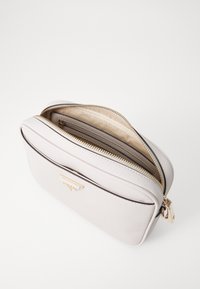 Borsa in pelle bianca con texture, zip dorata, forma rotonda e tasca interna con zip. Accentuata da un dettaglio in metallo dorato sulla parte anteriore.