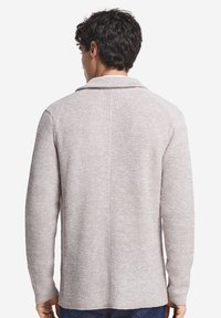 Teksturowany beżowy sweter z długimi rękawami, z kołnierzem szalowym i prostym krojem. Posiada subtelną tkaną strukturę oraz gładki tył.