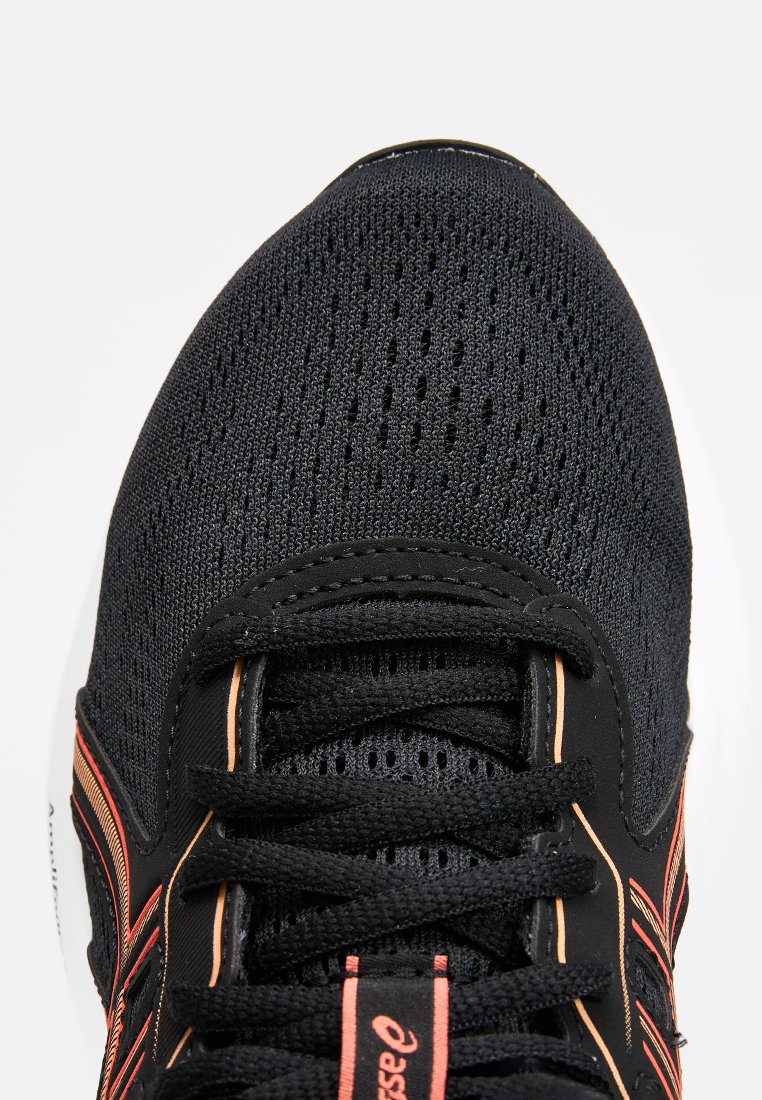 Scarpa sportiva nera con una tomaia in rete, caratterizzata da una finitura texturizzata, accenti arancioni e lacci neri su una suola bianca.