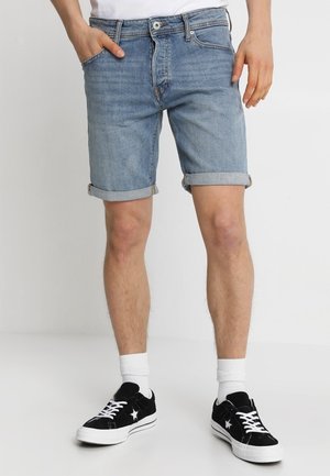 Lichte blauwe denimshorts met opgerolde zomen, vijf-pocket ontwerp en een klassieke knoopsluiting aan de voorkant. Draagt met zwarte sneakers en witte sokken.