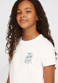 Hvid T-shirt med korte ærmer, der har et blåt palmetræsgrafik og logo på brystet. Blødt bomuldsmateriale med klassisk crew neck-design.