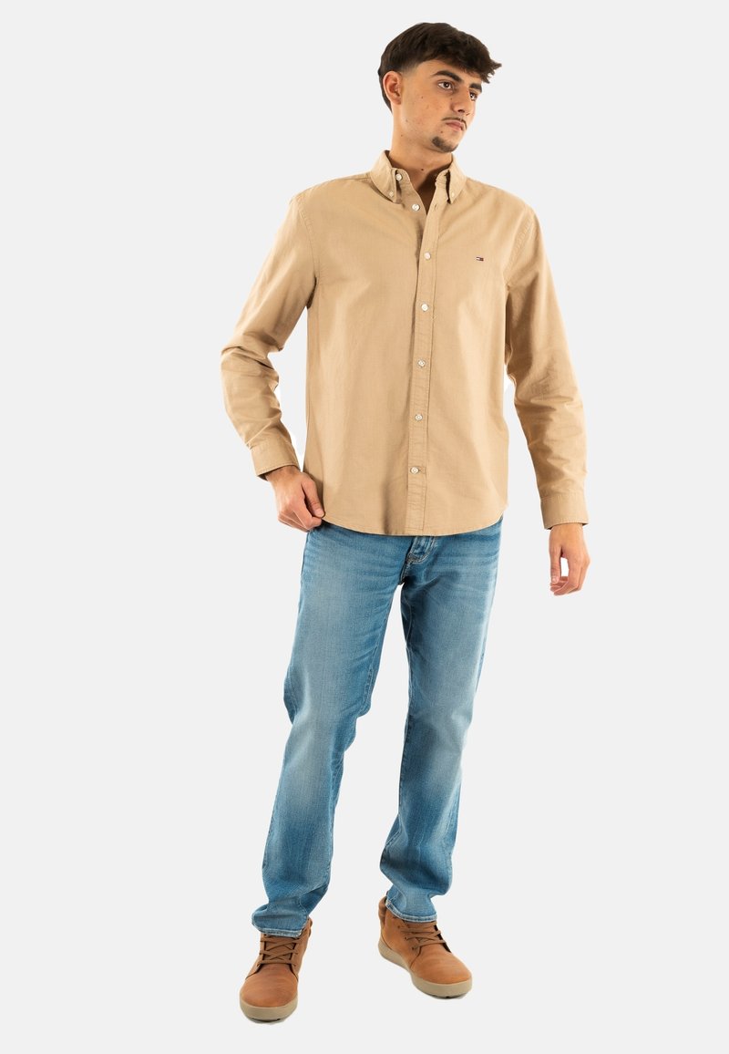 Lichtbruine button-up shirt met een kraag, gecombineerd met blauwe spijkerbroek en bruine veterschoenen. Eenvoudig ontwerp, gemaakt van katoen.