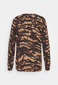 Camicia a maniche lunghe di colore beige con un motivo a strisce tigre marroni e nere ondulate. Tessuto morbido e leggero con una vestibilità rilassata e scollatura rotonda.