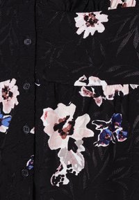 Black fabric dress featuring a floral pattern in pale pink, blue, and black. Textured surface with buttons and a gathered section.