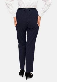 Marineblaue, taillierte Hose aus strukturiertem Stoff mit einem elastischen Bund, geradem Beinschnitt, kombiniert mit schwarzen High-Heels.