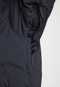 Navy jacket featuring a zippered pocket with mesh lining, textured exterior, and a smooth fabric finish, offering both functionality and comfort.