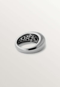 Anillo de plata redondeado con un acabado brillante, que presenta un interior negro con recortes circulares para añadir textura y detalle de diseño.