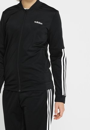 Survêtement noir Adidas avec un design à trois bandes blanches sur les manches et le pantalon, veste zippée et logo de la marque sur la poitrine.