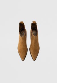 Botine din suede maro, cu vârfuri ascuțite, cu curbe de tragere și o căptușeală interioară netedă. Au un sole texturat pentru aderență.