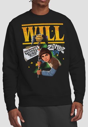 Person wearing black sweatshirt featuring character Will holding axe, with text "WILL," "Stranger Things Tales from '85," and "Zombie Boy."