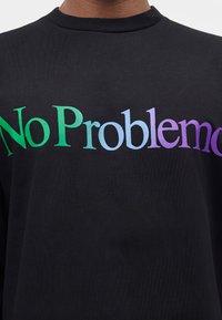 Μαύρο μπλουζάκι με στρογγυλή λαιμόκοψη με τη φράση «No Problemo» σε μεγάλα γράμματα με διαβάθμιση από πράσινο σε μωβ στο στήθος.