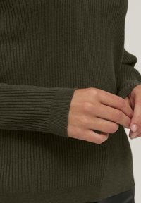 Pulover ribdat de culoare verde măslin, cu mâneci lungi și manșete texturate, realizat dintr-un material moale cu o ușoară elasticitate.