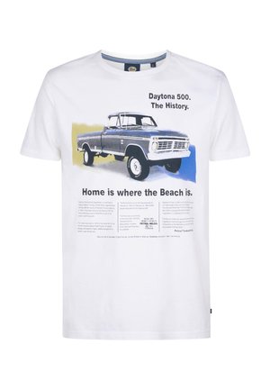 Camiseta de algodón blanca con un gráfico de un camión vintage azul, texto relacionado con el Daytona 500 y detallada información histórica debajo.