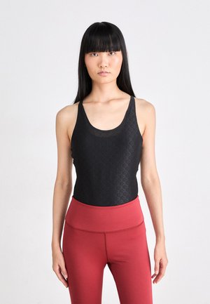 Must must näkemisega must tank top geomeetrilise mustriga, valmistatud sujuvast kangast, koos punaste kõrge vöökohtadega legginsitega, millel on lai vöökoht.