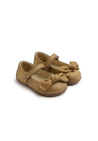 Zapatos Mary Jane de ante en color marrón claro, con punta redonda, detalle de lazo en la parte delantera y una correa asegurada sobre el empeine, que cuentan con una suela de goma marrón.