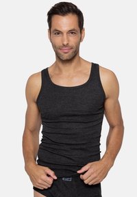 Black ribbed tank top made from soft fabric, featuring a snug fit and wide shoulder straps. Model is wearing it with matching briefs.