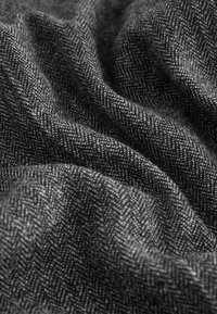 Black and gray woven fabric with a herringbone pattern, shown in soft folds highlighting texture and detail.
