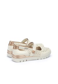 Scarpe bianche in pelle perforata con cinturino, dettagli dorati sul tacco e suola imbottita per comfort e supporto.