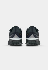 Ciemnoniebieskie buty do biegania po szlakach mają teksturowaną cholewkę z etykietą Gore-Tex, szare akcenty oraz wytrzymałą czarną podeszwę z wyraźnym bieżnikiem.
