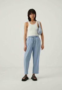 Heledad sinine paelaga püksid, valge ribaga tank top, mustad sandaalid ja väike heledad sinine õlakott. Lihtne disain pehmest kangast.