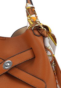 Kastanjebruine leren handtas met een gestructureerd oppervlak, voorzien van een decoratieve zijden sjaal die aan de handgreep is geknoopt. Zilveren hardware-accenten en gestikte details.