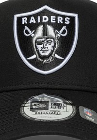 Schwarze Baseballmütze mit einem gestickten silber-weißen Raiders-Logo und einem verstellbaren New Era-Schild an der Innenseite des Schirms.