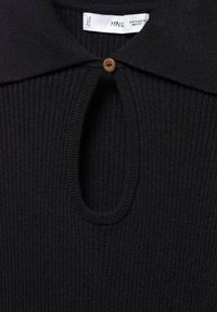 Haut noir en maille côtelée avec un col, présentant une découpe ovale au niveau du cou et une fermeture à bouton marron. Texture douce avec des coutures détaillées.