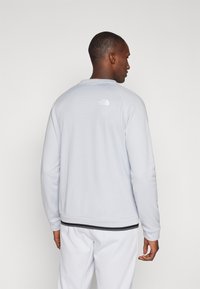 Sweatshirt cinza claro com um design texturizado, punhos canelados e uma risca preta na barra. Apresenta um pequeno logótipo branco nas costas.
