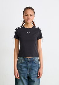 Tricou scurt cu mânecă neagră, cu dungi albe pe umeri, având panglici reglabile la mâneci și un mic logo alb pe piept.