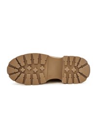Semelle marron épaisse de chaussure avec des crampons profonds et des motifs en forme de croix, taille 38 visible sur la section centrale lisse.