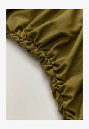 Tessuto verde oliva con una superficie testurizzata, caratterizzato da bordi elastici arricciati per un design aderente. Materiale morbido e elasticizzato.