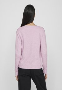 Maglioncino rosa chiaro lavorato a maglia con maniche lunghe, scollatura tonda e orlo a coste. Tessuto morbido, design informale e vestibilità comoda.