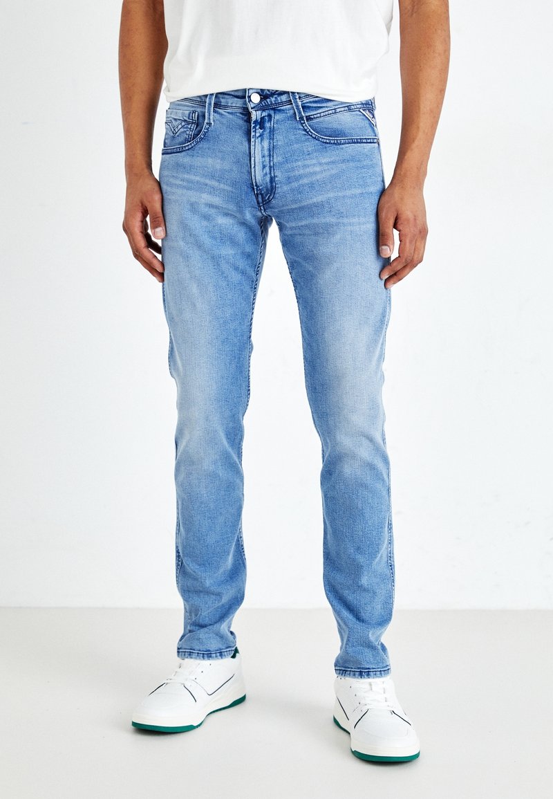 Ljusblå jeans i denim, med en figursydd design, fem fickor och subtil blekning. Bärs med vita sneakers.